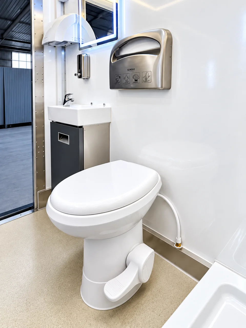 Toilet and wall-mounted sink inside a commercial mobile restroom trailer