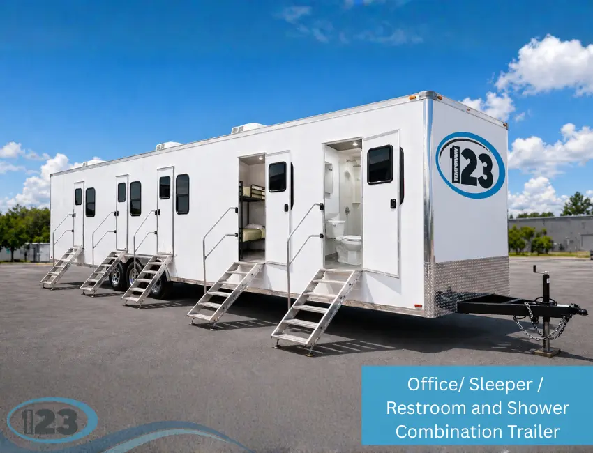 White combination trailer with office, sleeper, restroom, and shower areas. Features multiple doors and entry steps under a sunny blue sky.